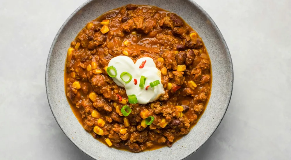Chilis bab tálalva, egészséges egytálétel zöld díszítéssel az asztalon