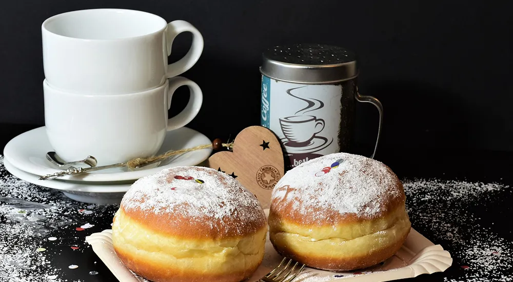 Kávés poharak süteménnyel és cappuccinóval tálcán