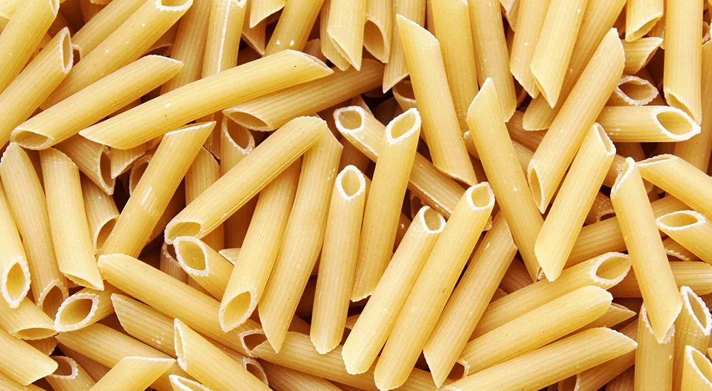 Nyers durum penne tészta sárga színben, közelről fotózva nagyban