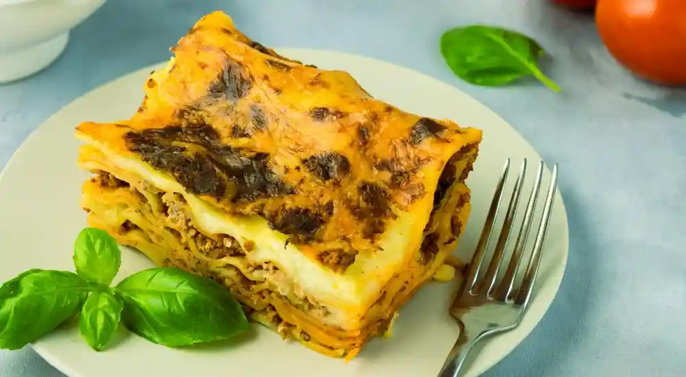 Sült lasagne friss paradicsommal és zöldségekkel tálalva
